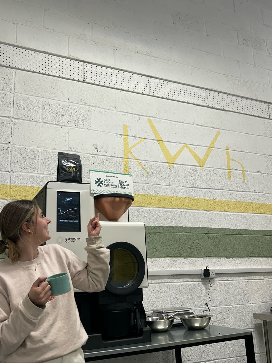 Caitlin beside the electric Bellwether roaster at the kWh roastery in York